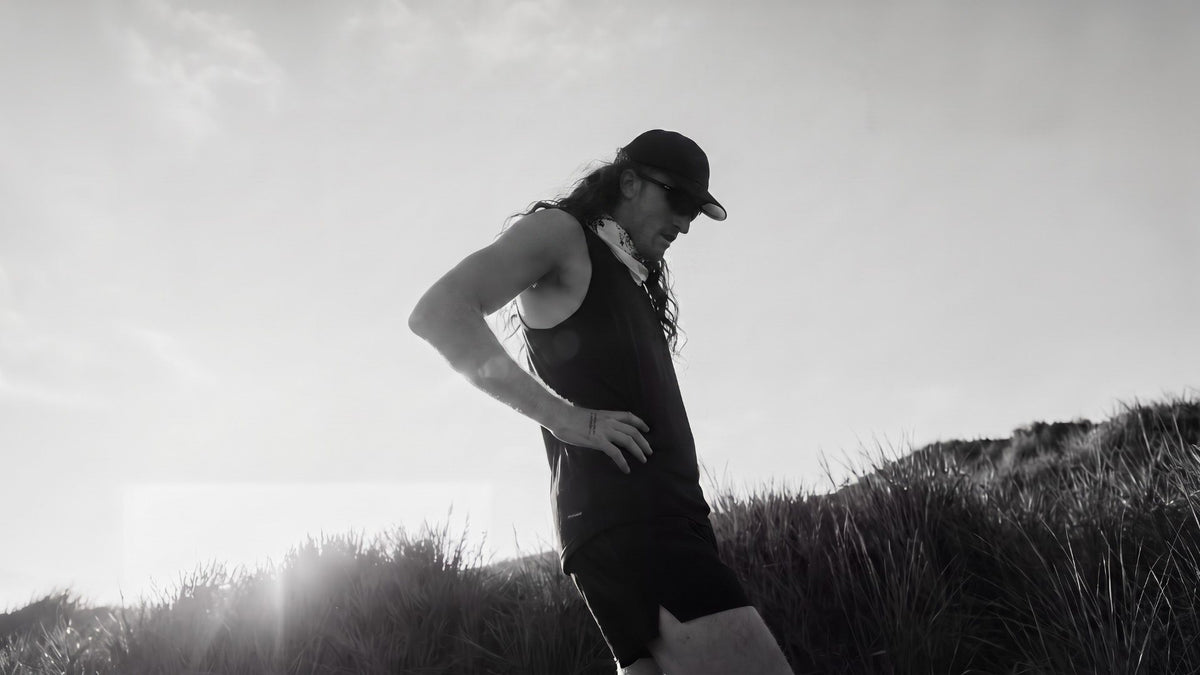 Runner pausing with a hand on the hip in low sun after a long run