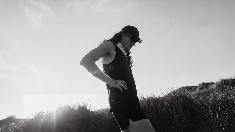 Runner pausing with a hand on the hip in low sun after a long run